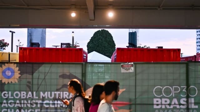 Personas caminan junto a generadores eléctricos que funcionan con diésel a las afueras del Centro de Convenciones Hangar donde se realiza la COP30, este lunes 17 de noviembre de 2025 en Belém, Brasil. (EFE/ Andre Borges)