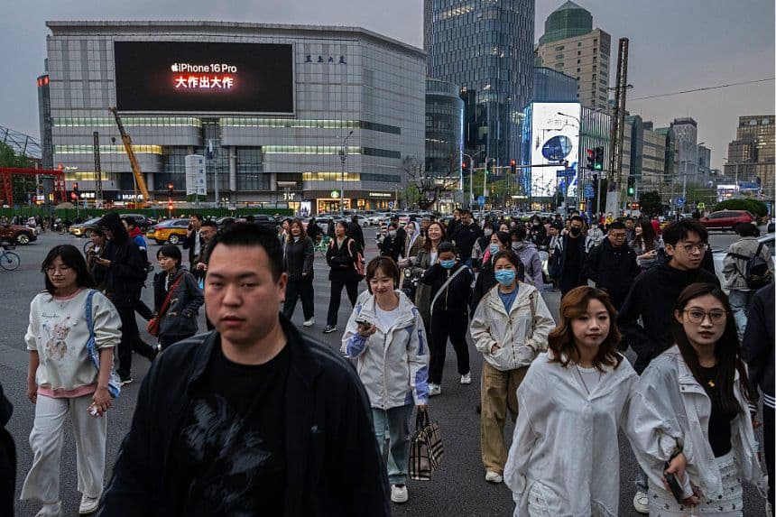 La gente cruza un semáforo mientras una pantalla muestra un anuncio del iPhone 16 de Apple el 8 de abril de 2025 en Beijing, China. (Kevin Frayer/Getty Images)