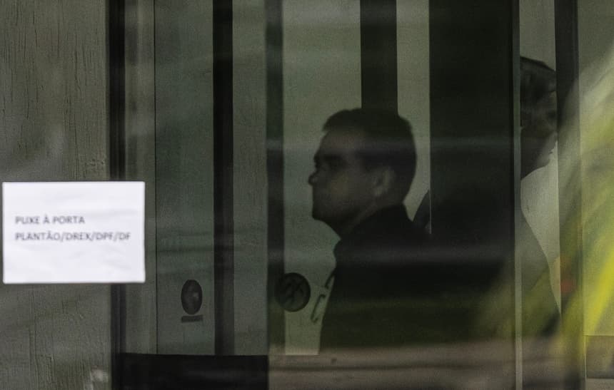 Fotografía que muestra al expresidente de Brasil Jair Bolsonaro (d) detrás de una puerta de vidrio el domingo 23 de noviembre de 2025, en la Superintendencia de la Policía Federal en Brasilia, Brasil. (EFE/ Isaac Fontana)