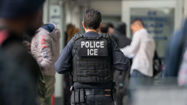 NEW YORK, NEW YORK - JUNE 6: An ICE agent monitors hundreds of asylum seekers being processed upon entering the Jacob K. Javits Federal Building on June 6, 2023 in New York City. New York City has provided sanctuary to over 46,000 asylum seekers since 2013, when the city passed a law prohibiting city agencies from cooperating with federal immigration enforcement agencies unless there is a warrant for the person's arrest.(Photo by David Dee Delgado/Getty Images)