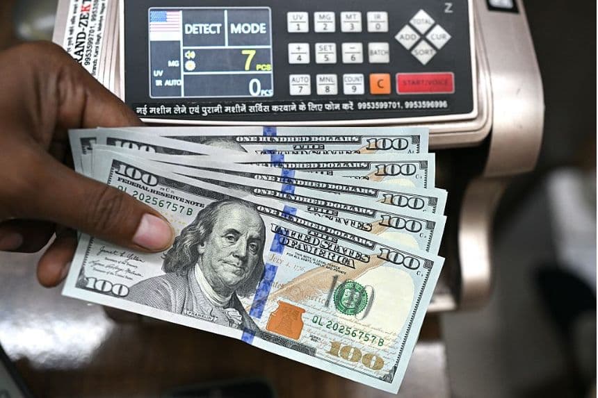 Un trabajador sostiene billetes de dólar estadounidense y posa para una fotografía en una casa de cambio en Nueva Delhi, el 31 de julio de 2025. (ARUN SANKAR/AFP a través de Getty Images)