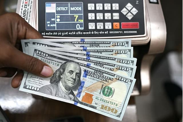 Un trabajador sostiene billetes de dólar estadounidense y posa para una fotografía en una casa de cambio en Nueva Delhi, el 31 de julio de 2025. (ARUN SANKAR/AFP a través de Getty Images)