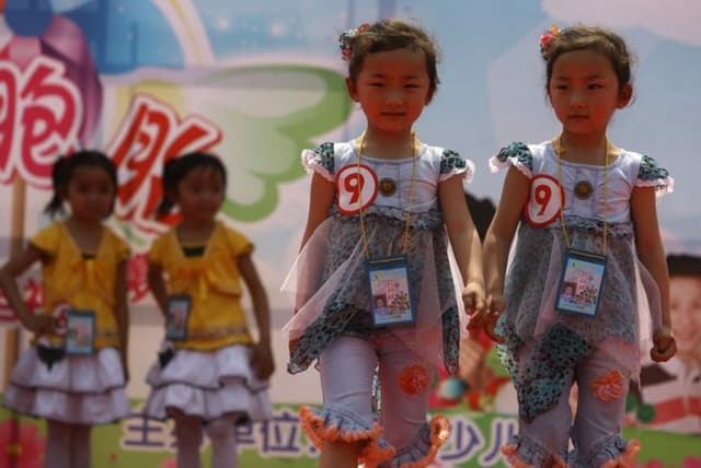 Un par de gemelas desfilan por la pasarela durante el Concurso Provincial de Talentos de Gemelas de Jiangsu, en Nanjing, provincia de Jiangsu, China, el 4 de mayo de 2006. (Fotos de China/Getty Images)