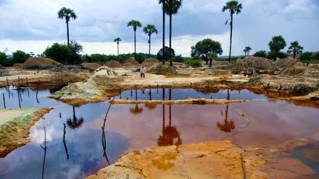 Esta fotografía, tomada el 31 de agosto de 2013, muestra a un trabajador caminando junto a unos estanques en una zona de vertido de residuos mineros en Monywa, al noroeste de Myanmar. Los aldeanos cuyas tierras fueron expropiadas por la antigua junta militar en esta región rica en cobre utilizan tierra desechada de las minas cercanas, mezclada con latas de aluminio viejas, agua y ácido, para recuperar el cobre de los residuos. Trabajando ilegalmente y sin equipo de seguridad, los aldeanos se exponen a riesgos para la salud con el fin de ganarse la vida. AFP PHOTO/Ye Aung THU (Foto de Ye Aung THU / AFP) (Foto de YE AUNG THU/AFP a través de Getty Images).