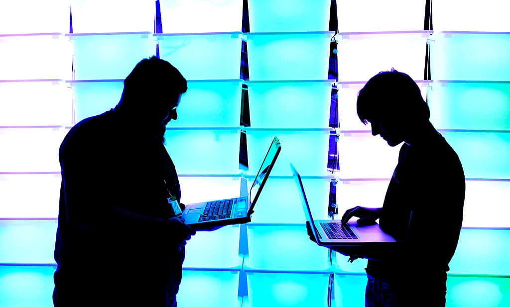 Los participantes sostienen sus ordenadores portátiles frente a una pared iluminada en el congreso anual de hackers informáticos del Chaos Computer Club (CCC), denominado 29C3, el 28 de diciembre de 2012 en Hamburgo, Alemania. (Foto de Patrick Lux/Getty Images)