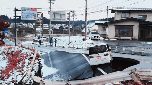 Un vehículo descansa al borde de una carretera derrumbada en la localidad de Tohoku, en la prefectura de Aomori, el 9 de diciembre de 2025, tras un terremoto de magnitud 7.5 frente a la costa norte de Japón. Un gran terremoto frente a la costa norte de Japón dejó al menos 30 heridos, según informaron las autoridades el 9 de diciembre, dañando carreteras y dejando a miles de personas sin electricidad en temperaturas bajo cero. (JIJI Press / AFP a través de Getty Images) / Japón OUT