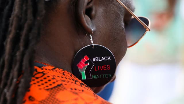 Una mujer con pendientes con el lema "Black Lives Matter" se une a la gente reunida en Windrush Square, Brixton, para celebrar el 76.º aniversario de Windrush el 23 de junio de 2024 en Londres, Inglaterra. (Foto de Alishia Abodunde/Getty Images)