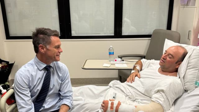 Fotografía publicada en el perfil de X del líder político de Nueva Gales del Sur, Chris Minns, que muestra a Minns (i) visitando en el hospital a Ahmed al Ahmed, el hombre que desarmó a uno de los autores del atentado perpetrado ayer en Sídney. Junto a la fotografía, Minns define a Ahmed como "un héroe de verdad" cuya "increíble valentía sin duda salvó innumerables vidas al desarmar a un terrorista con un enorme riesgo personal". Ahmed, de 43 años, se escondió el domingo detrás de unos vehículos para sorprender a uno de los asaltantes y forcejear con él hasta quitarle con sus propias manos el rifle con el que disparaba a los transeúntes en la popular playa de Bondi. Como consecuencia, Ahmed recibió disparos en el brazo y la mano. (EFE/ Chris Minns vía red social X)