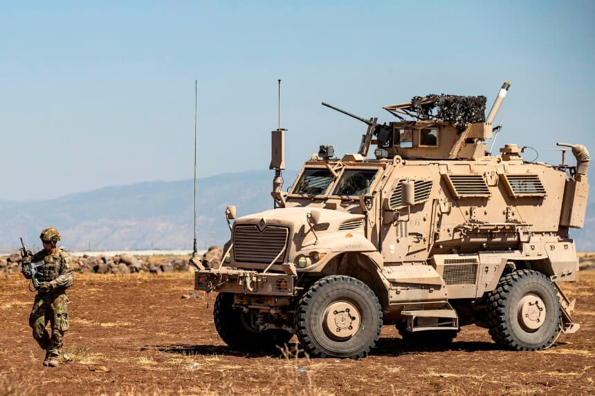 A US soldier stands in front of a military vehicle patroling near the city of Al-Malikiyah in the northeastern Syrian Al-Hasakah governorate, near the Turkish border, on August 27, 2020. (Photo by Delil SOULEIMAN / AFP) (Photo by DELIL SOULEIMAN/AFP via Getty Images)