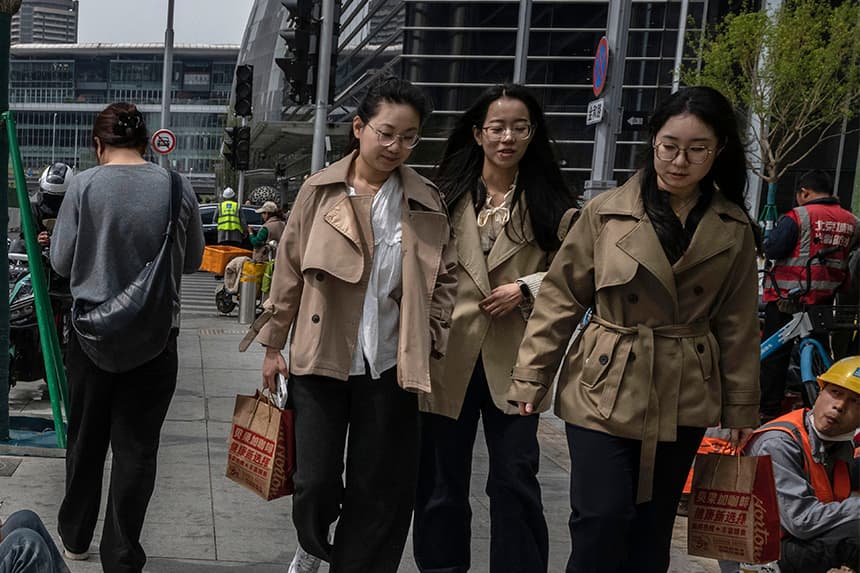 Empleados de oficina pasan junto a trabajadores de la construcción en el distrito central de negocios el 9 de abril de 2025 en Beijing, China. (Kevin Frayer/Getty Images).