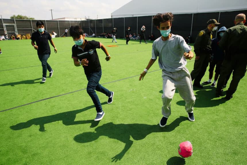 Menores de edad juegan al fútbol en un pequeño campo del centro de detención del Departamento de Seguridad Nacional de Donna, el principal centro de detención para niños no acompañados en el valle del Río Grande gestionado por la Oficina de Aduanas y Protección Fronteriza de Estados Unidos (CBP), en Donna, Texas, el 30 de marzo de 2021. (DARIO LÓPEZ-MILLS/POOL/AFP a través de Getty Images)