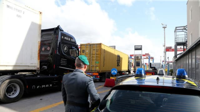 Un agente de la Guardia di Finanza, la policía italiana encargada de los delitos financieros y el contrabando, revisa camiones que transportan contenedores en la zona comercial del puerto de Nápoles, el 29 de febrero de 2024. (CARLO HERMANN/AFP vía Getty Images)