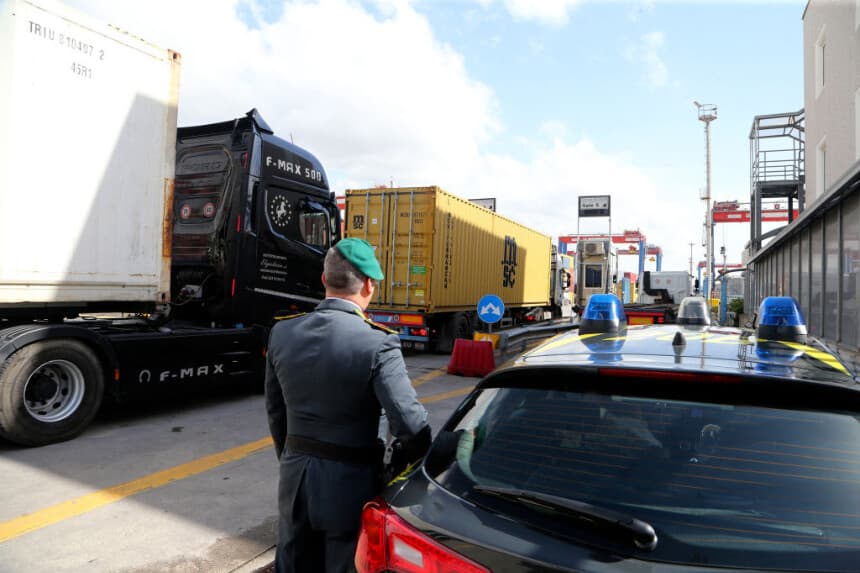Un agente de la Guardia di Finanza, la policía italiana encargada de los delitos financieros y el contrabando, revisa camiones que transportan contenedores en la zona comercial del puerto de Nápoles, el 29 de febrero de 2024. (CARLO HERMANN/AFP vía Getty Images)