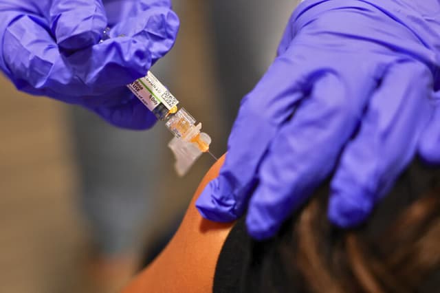 Una persona es vacunada durante una campaña de inmunización en el Centro de Recursos Comunitarios L.A. Care y Blue Shield of California Promise Health Plan, en el barrio Panorama City de Los Ángeles, California, el 24 de octubre de 2025. (Foto de Patrick T. Fallon / AFP) (Foto de PATRICK T. FALLON/AFP a través de Getty Images).