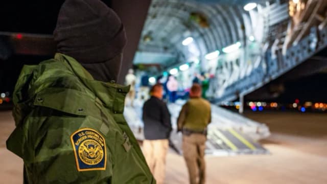 Un agente de Aduanas y Protección Fronteriza de EE. UU. observa cómo se suben inmigrantes ilegales a un avión en el Aeropuerto Internacional de Tucson en Tucson, Arizona, el 23 de enero de 2025. (Aviador sénior Devlin Bishop/DOD)