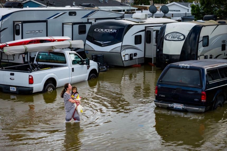La gente camina por un estacionamiento de caravanas inundado por las "mareas gigantes", que se producen cuando el Sol, la Luna y la Tierra se alinean, lo que provoca una mayor atracción gravitatoria el sábado 3 de enero de 2026, cerca de Corte Madera, en el condado de Marin, California. (Ethan Swope/Foto AP)