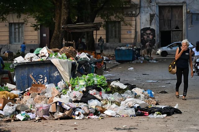 Una mujer se tapa la nariz al pasar junto a la basura en una calle de La Habana el 4 de diciembre de 2025. Veintiún niños se encuentran entre las 33 personas que han fallecido en Cuba a causa de los virus del chikunguña y el dengue, transmitidos por mosquitos, desde julio, según informaron las autoridades el lunes. (YAMIL LAGE/AFP a través de Getty Images)