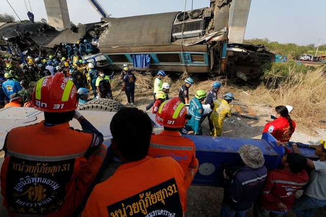 Los equipos de rescate transportan el cuerpo de una víctima en el lugar donde una grúa de construcción se derrumbó sobre un tren en el distrito de Sikhio, Nakhon Ratchasima, Tailandia, el 14 de enero de 2026. (EFE/EPA/NARONG SANGNAK)
