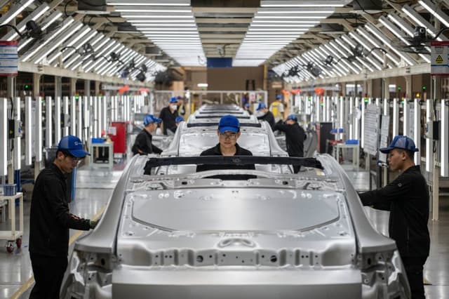 Trabajadores revisan los chasis de los vehículos en la línea de producción del fabricante de vehículos eléctricos Zeekr en su fábrica el 29 de mayo de 2025 en Ningbo, China. (Kevin Frayer/Getty Images)