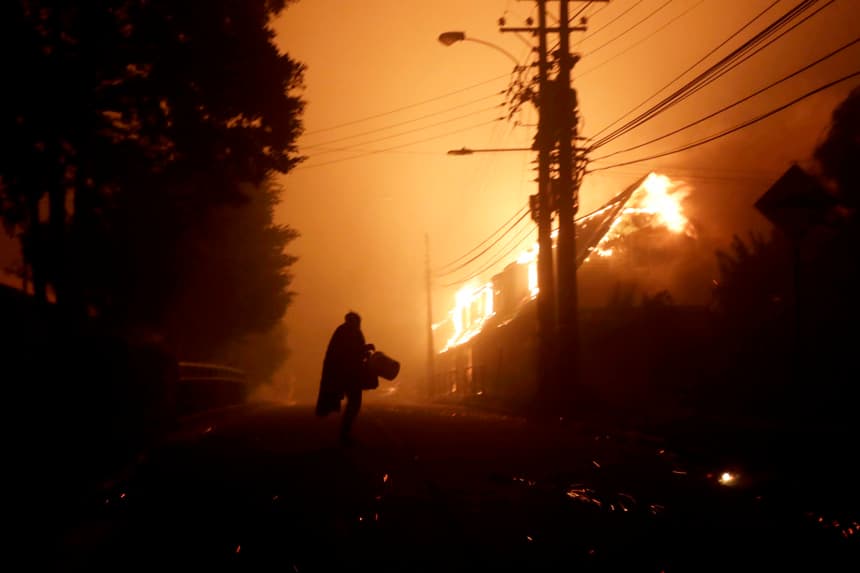 Una persona evacua un área de casas afectadas por los incendios forestales la madrugada de este domingo, en Penco, Chile. (EFE/ Patricio Aguayo)
