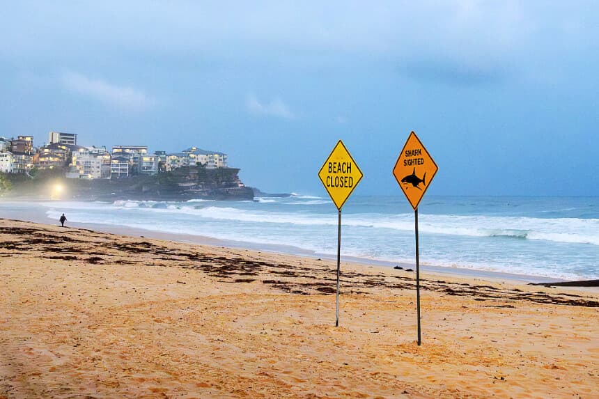 Un visitante camina por la costa cerca de la señal de cierre de la playa North Steyne en Sídney el 19 de enero de 2026. Un tiburón atacó a un surfista en una playa de Sídney el 19 de enero, en lo que supone el tercer ataque de tiburón en dos días en la ciudad australiana, según informaron las autoridades. (Steven Markham / AFP vía Getty Images)