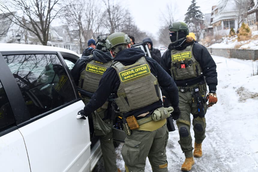 Agentes federales regresan a su coche tras una patrulla en el barrio de Frogtown, mientras activistas contrarios al ICE advierten a la comunidad de su presencia y se oponen a las detenciones que está llevando a cabo el Servicio de Inmigración y Control de Aduanas, en el marco de las crecientes tensiones tras el aumento de las medidas federales de control de la inmigración y el reciente tiroteo en el que se vio involucrado un agente del ICE en St. Paul, Minnesota, el 16 de enero de 2026. El presidente de los Estados Unidos, Donald Trump, dijo el viernes que no había necesidad inmediata de invocar la Ley de Insurrección por las protestas contra las redadas de inmigración en Minnesota, un día después de amenazar con recurrir a dicha ley. Trump había amenazado con tomar esta drástica medida, que le habría permitido desplegar al ejército en el estado del norte con fines policiales, en respuesta a las protestas contra las redadas de inmigración de amplio alcance encabezadas por su administración. (Foto de Octavio JONES / AFP a través de Getty Images).