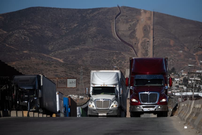 En esta imagen ilustrativa se ven camiones de carga hacer fila junto al muro fronterizo antes de cruzar hacia los Estados Unidos en el puerto comercial de Otay en Tijuana, estado de Baja California, México, el 31 de julio de 2025.(GUILLERMO ARIAS/AFP via Getty Images)