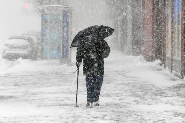 NUEVA YORK, NY - 4 DE ENERO: Un peatón con un paraguas cruza la calle en Harlem durante una tormenta de nieve el 4 de enero de 2018 en la ciudad de Nueva York. A medida que una gran tormenta invernal avanza por el corredor noreste, la ciudad de Nueva York se encuentra bajo una alerta de tormenta invernal y las previsiones anuncian entre 15 y 20 centímetros de nieve. (Foto de Dia Dipasupil/Getty Images).
