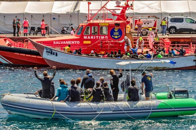 Una lancha neumática pasa junto a un barco del Salvamento Marítimo español que escolta a un cayuco con 81 migrantes, entre ellos 3 mujeres y 3 niños, en el puerto de La Restinga, en la isla canaria de El Hierro, el 9 de septiembre de 2024. (Antonio Sempere/AFP vía Getty Images)