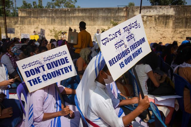 Monjas de la comunidad Misioneras de la Caridad de la Madre Teresa sostienen carteles mientras escuchan a un orador durante una manifestación contra la presentación del proyecto de ley de Protección del Derecho a la Libertad Religiosa en Bangalore, India, el 22 de diciembre de 2021. Abhishek Chinnappa/Getty Images.