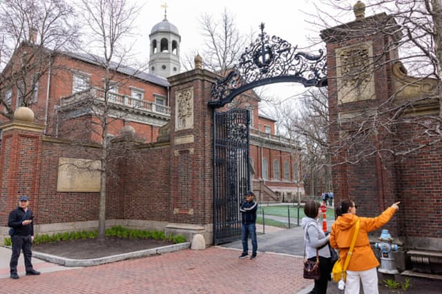 Turistas frente a la puerta principal de Harvard Yard el 15 de abril de 2025 en Cambridge, Massachusetts. Un grupo de trabajo de la administración Trump anunció el lunes que impediría a la Universidad de Harvard recibir 2200 millones de dólares en subvenciones federales y 60 millones de dólares en contratos después de que la universidad de la Ivy League desafiara las exigencias de adoptar nuevas políticas sobre la conducta y la admisión de estudiantes y profesores. (Foto de Scott Eisen/Getty Images).