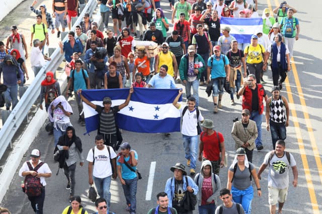 Miembros de la caravana de migrantes portan banderas de Honduras (izquierda) y Nicaragua (derecha) mientras caminan tras cruzar la frontera guatemalteca hacia México el 21 de octubre de 2018 cerca de Ciudad Hidalgo, México. (John Moore/Getty Images)