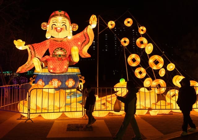 Personas caminan cerca de decoraciones relacionadas con el Año Nuevo Chino en Beijing. EFE/EPA/JESSICA LEE