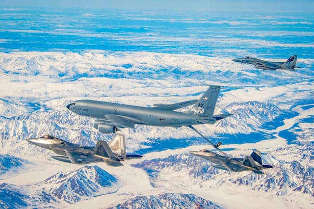 Un KC-135 Stratotanker del 168.º Ala de Reabastecimiento Aéreo reabastece a los F-22 Raptors del 3.º Ala sobre el Complejo Conjunto del Pacífico y Alaska, volando junto a un F-15 Eagles del 144.º Ala de Caza, el 18 de abril de 2022. (Foto de la Guardia Aérea Nacional tomada por el sargento mayor Charles Vaughn).