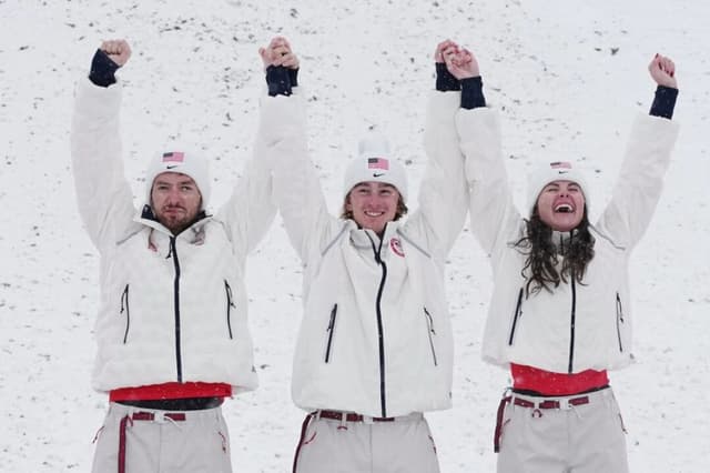 (De Izq. a Der.) Los medallistas de oro estadounidenses Christopher Lillis, Connor Curran y Kaila Kuhn celebran después de la final de esquí acrobático por equipos mixtos en los Juegos Olímpicos de Invierno de 2026, en Livigno, Italia, el 21 de febrero de 2026. (Gregory Bull/AP Photo)