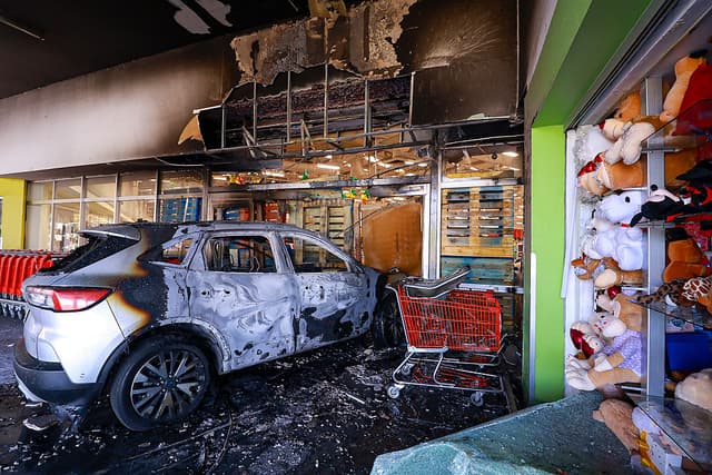 Un auto incendiado impactó la entrada de una tienda en un centro comercial el 22 de febrero de 2026 en Guadalajara, México. Se han reportado bloqueos viales e incendios de vehículos en varias zonas de México desde la madrugada. La Secretaría de la Defensa Nacional confirmó que, durante un operativo de seguridad en Tapalpa, Jalisco, Nemesio Oseguera Cervantes, conocido como "El Mencho", líder del Cártel Jalisco Nueva Generación, fue asesinado junto con otros cuatro miembros. Tres soldados mexicanos resultaron heridos durante el operativo. (Carlos Zepeda/Getty Images)