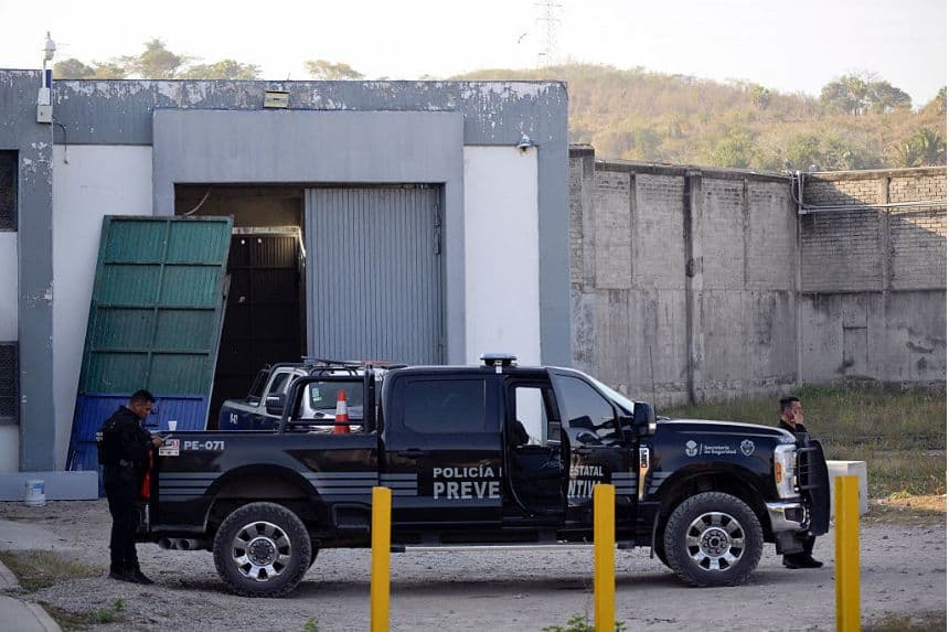 Miembros de la policía se encuentran frente al penal con la puerta derribada, de donde escaparon 23 reclusos el domingo pasado, en Puerto Vallarta, estado de Jalisco, México, el 24 de febrero de 2026. (Alfredo ESTRELLA / AFP a través de Getty Images)