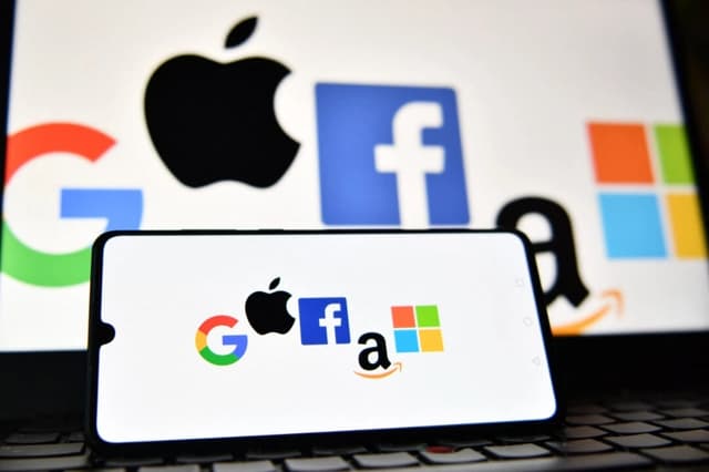 Los logotipos de Google, Apple, Facebook, Amazon y Microsoft en la pantalla de un teléfono móvil y una computadora portátil. (Justin Tallis/AFP vía Getty Images)