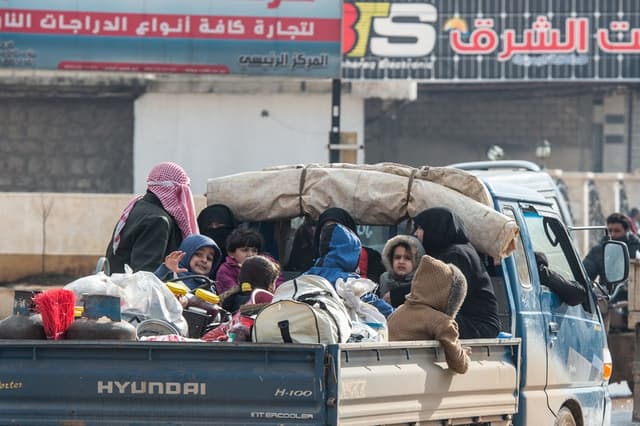 Una familia siria desplazada viaja en la parte trasera de un camión cargado con las pertenencias de la familia el 22 de febrero de 2020 en Idlib, Siria. (Burak Kara/Getty Images)