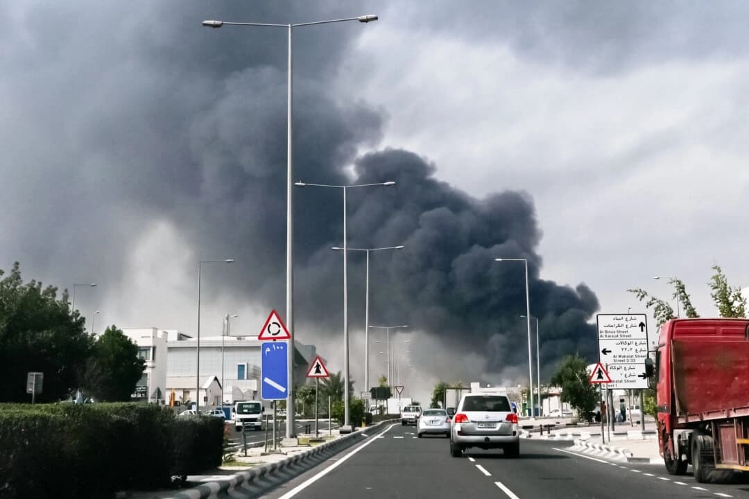 Automovilistas pasan junto a una columna de humo que se eleva desde un supuesto ataque iraní en el distrito industrial de Doha, Qatar, el 1 de marzo de 2026. (Mahmud HAMS / AFP vía Getty Images)