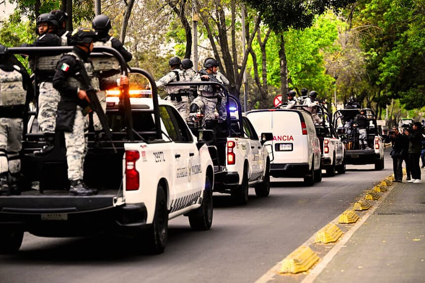 Las fuerzas especiales de la Guardia Nacional Mexicana escoltan una ambulancia del servicio forense a su llegada a la sede de la Fiscalía Especializada para la Defensa de la Justicia en materia de Delitos Organizados (FEMDO) en la Ciudad de México, el 22 de febrero de 2026. (Foto de Alfredo ESTRELLA / AFP vía Getty Images)
