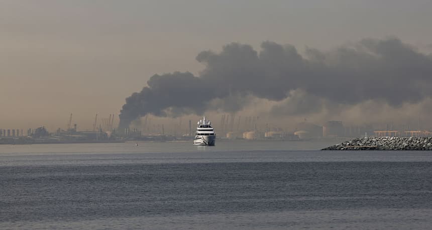 Un yate navega junto a una columna de humo que se eleva desde el puerto de Jebel Ali tras un supuesto ataque iraní en Dubái, el 1 de marzo de 2026. (Fadel SENNA/AFP vía Getty Images)