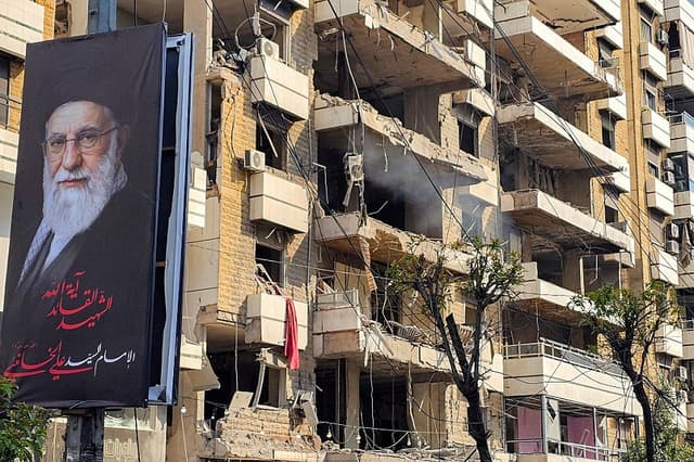 Una pancarta del líder supremo de Irán, el ayatolá Alí Jamenei, junto a un edificio dañado por un ataque israelí en los suburbios del sur de Beirut, el 3 de marzo de 2026. (AFP vía Getty Images)