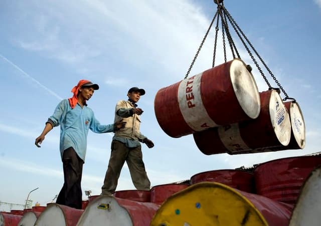 Dos operarios descargan barriles cargados de petróleo. Imagen de archivo. (EFE/Adi Weda)