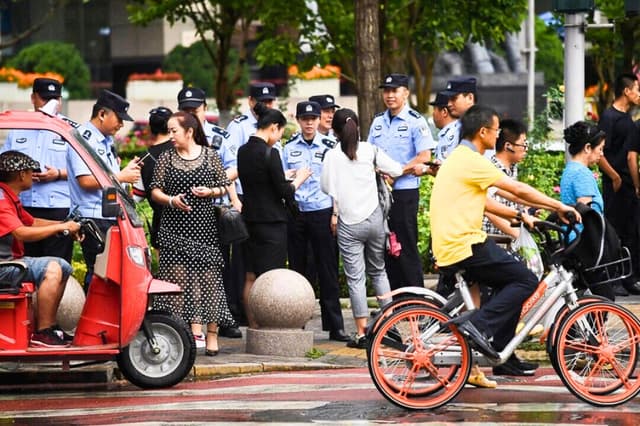 La policía comprueba la identificación de los transeúntes mientras busca a los solicitantes cerca de la Comisión Reguladora Bancaria de China en Pekín, el 6 de agosto de 2018. (Greg Baker/AFP a través de Getty Images).