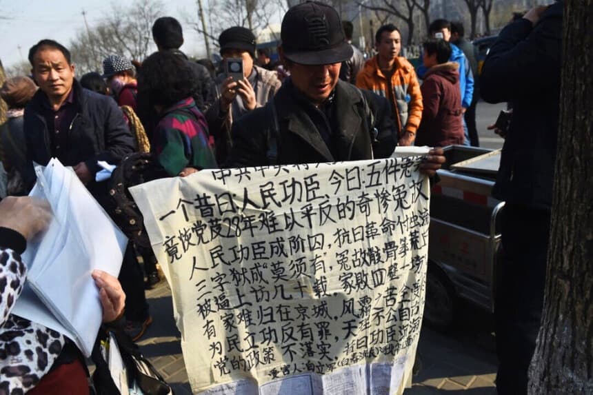 Un hombre sostiene una pancarta de protesta frente a la oficina central de peticiones en Beijing el 2 de marzo de 2016. (Greg Baker/AFP/Getty Images).
