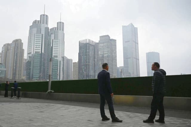 Dos hombres charlan frente a unos edificios de oficinas en el distrito financiero central de Beijing, el 4 de marzo de 2026. (Greg Baker/AFP vía Getty Images).