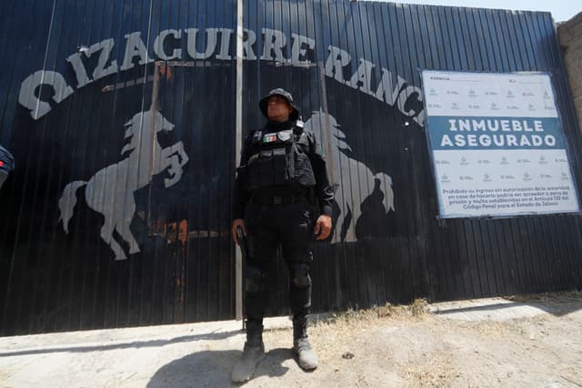 Fotografía de archivo del 20 de marzo de 2025 de un integrante de la fiscalía estatal resguardando la entrada al Rancho Izaguirre en el municipio de Teuchitlán, Jalisco (EFE/ Francisco Guasco)
