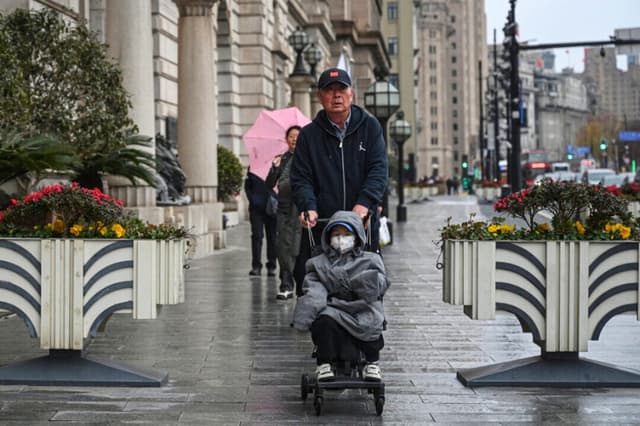 Un hombre empuja un cochecito con un niño por una calle del Bund, en Shanghái, el 19 de enero de 2026. (Jade Gao/AFP a través de Getty Images).