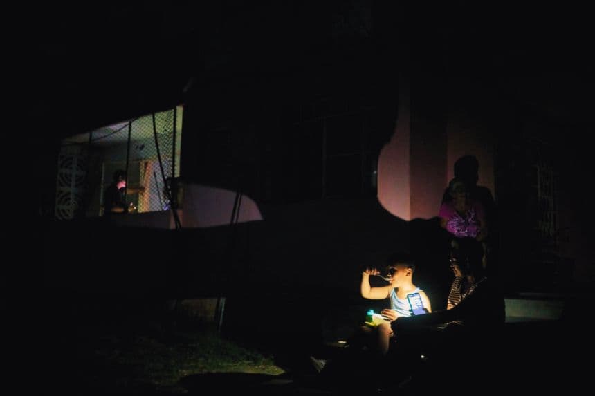 Los residentes del barrio de Naranjal Norte permanecen frente a sus hogares para recibir una cena fresca y generosa a la luz de la linterna de un celular durante un corte de energía nocturno de siete horas en la provincia de Matanzas, Cuba, el 30 de mayo de 2024. (ANTONIO LEVI/AFP vía Getty Images)
